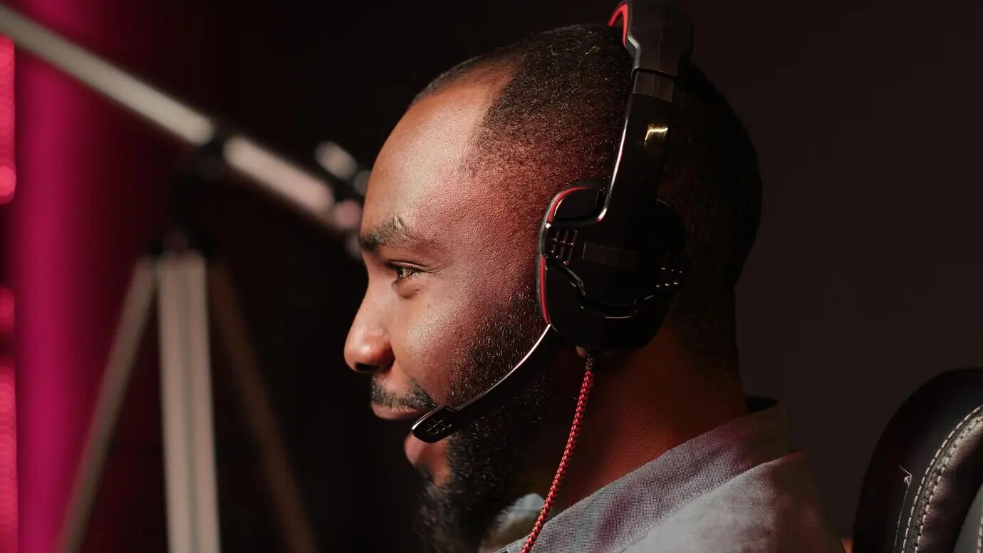 Ein Mann lacht, während er am Gaming-PC spielt und mit seinen Kumpels spricht.